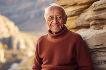 Poster - Portrait of a glad indian man in his 80s wearing a classic turtleneck sweater on rocky cliff background