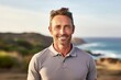 © Markus Schröder - Portrait of a smiling man in his 40s wearing a breathable golf polo isolated on serene seaside background