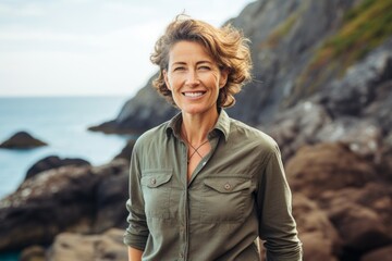 Wall Mural - Portrait of a glad woman in her 50s sporting a breathable hiking shirt isolated in rocky shoreline background