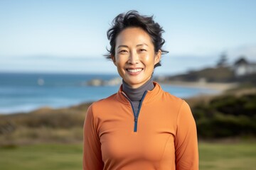 Wall Mural - Portrait of a grinning asian woman in her 40s wearing a breathable golf polo isolated in calm bay background