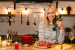 © InsideCreativeHouse - Adorable nice-looking middle-aged woman with rose sitting in the kitchen with romantic dinner on the table. Smiling lady celebrating special event birthday