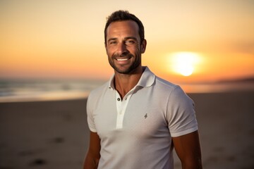 Wall Mural - Portrait of a smiling man in his 30s wearing a breathable golf polo in front of vibrant beach sunset background