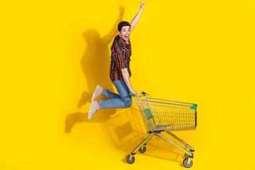 Wall Mural - Full length portrait of nice young man jump raise fist trolley wear shirt isolated on yellow color background