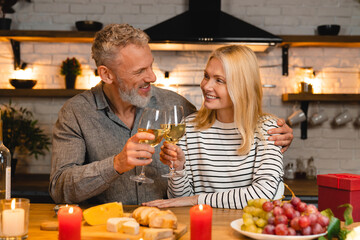 happy married couple celebrating special event during the romantic dinner in the kitchen while clink