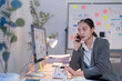 © Tj - Businesswoman is working late, analyzing financial data on her computer and discussing the results with a client on her phone