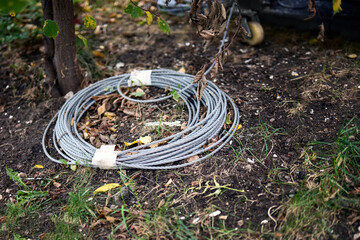 metal cable coiled into a circle rests on the grass, symbolizing the tension between nature and industry. The juxtaposition of the hard material against the soft grass evokes a sense of contrast