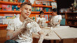 © Summit Art Creations - Happy student looking while put paintbrush behind ear in art lesson. Diverse student having pottery class together. Highschool boy smile while wearing white shirt with mud stained cloth. Edification.