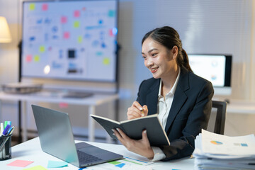 Smiling businesswoman works late at night in her office, taking notes and focusing on tasks. She exudes confidence and determination, embodying ambition and success in the corporate world