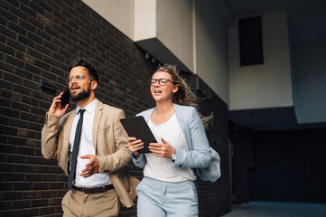 Business people running and talking on phone outside office building