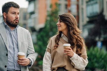 Business people talking and holding disposable coffee cups outdoors