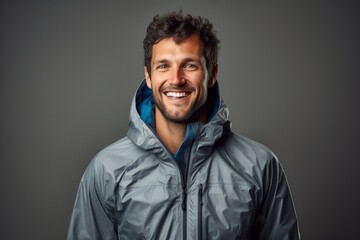 Wall Mural - Portrait of a smiling man in his 30s wearing a windproof softshell while standing against minimalist or empty room background