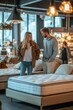 © Oscar - A couple looking at a variety of bed frames and mattresses in a modern showroom, while the salesperson shows them different options, both engaged and comparing styles and prices