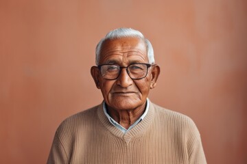 Wall Mural - Portrait of a glad indian man in his 80s showing off a thermal merino wool top on minimalist or empty room background