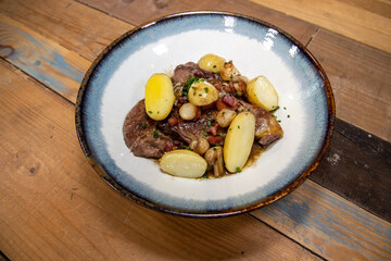 A delicious plate of chicken coq au vin with potatoes on a wooden kitchen work top