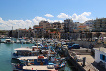 Fishing boats docked in harbor with tourists walking on pier