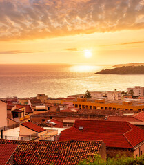 Wall Mural - wonderful landscape of beautiful mediterranean sunset town in Italy with orange old tile roofs, nice sea gulf coast, calm evening water and awesome yellow cloudy sky on background