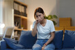 ©  NCST Studio - Young woman is sitting on her sofa at night, feeling unwell and coughing into her hand