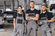 © anatoliycherkas - Group of three car service technician men and woman talking at workplace, people working together at vehicle repair garage service shop, check and repair customer car at automobile service center.