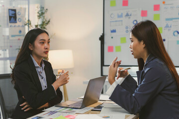 Two businesswomen are having a discussion about a new project, brainstorming ideas in a modern office