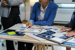 ©  NCST Studio - Business team in a meeting analyzing financial charts and graphs on desk with calculator and digital tablet