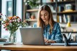 © irawan - Woman working on laptop at desk with flowers