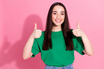 Photo of adorable lovely girl wear green t-shirt showing two thumbs up empty space isolated pink color background