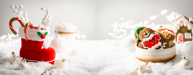 Wall Mural - christmas creative composition made with santa boots with sweets and gifts on snow background. minim
