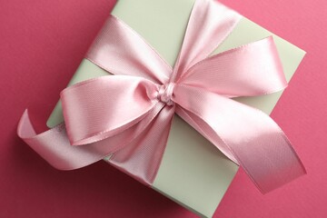 Poster - Beautiful gift box with bow on pink background, top view