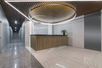 Modern design of the office lobby. The ceiling and reception area are decorated with wooden slats. Light floor tiles.