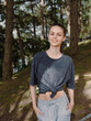 © SHOTPRIME STUDIO - Smiling young woman in casual outfit, standing outdoors in the forest, enjoying nature and a peaceful moment, embracing a carefree lifestyle