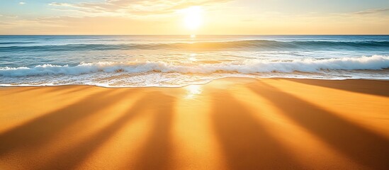 Wall Mural - golden beach at sunrise with soft waves crashing onto the shore casting long shadows across the sand