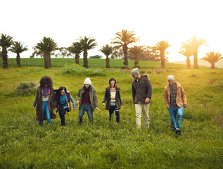 Aufkleber - Walking, field and friends with nature, travel and getaway trip with adventure, countryside and lens flare. Outdoor, people and group with grass, journey and bonding together with happiness or joyful