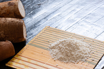 Three cassava roots next to a portion of flour