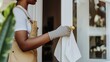 © fotofabrika - A person in gloves cleans a door handle in a sunlit home, emphasizing cleanliness and hygiene during daily chores