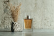 © Pisahouse - A stylish perfume bottle beside a textured rock and dried flowers, set against a minimalist concrete backdrop, creating an elegant aesthetic.