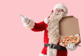 Wall Mural - Santa Claus with box of tasty pizza pointing at something on pink background