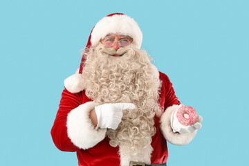 Poster - Santa Claus pointing at tasty donut on blue background