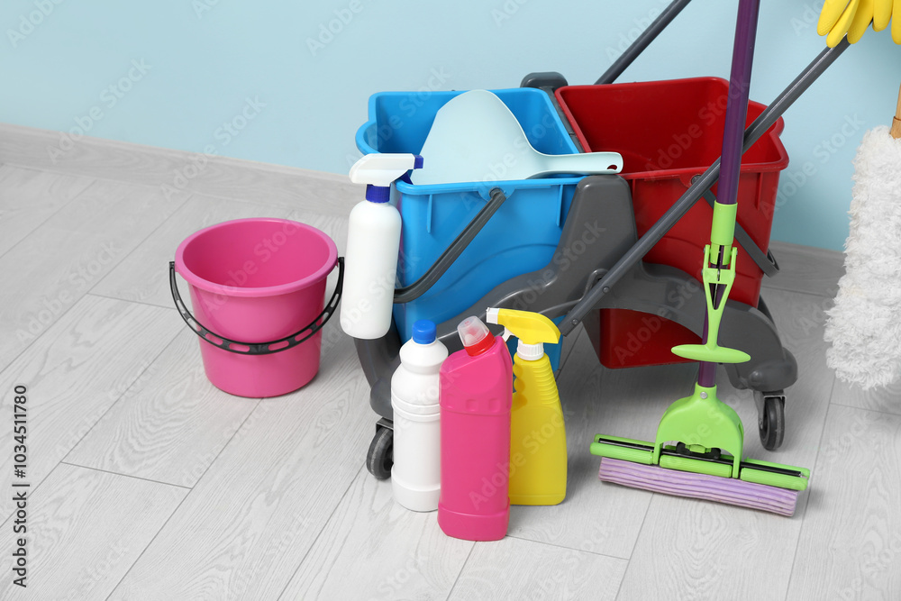 Janitor's trolley with cleaning supplies near blue wall