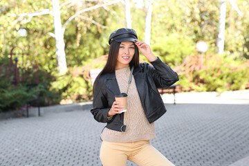 Canvas Print - Beautiful young happy Asian woman in leather black hat with cup of coffee at park