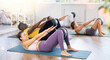 © JackF - Lying and sitting on mat Asian woman instructor conducts training with fit ball for multinational group students. Active movements in different planes, strengthening muscles of arms, legs, back, abs.