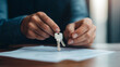 © NaphakStudio - person is holding set of keys above document, symbolizing significant transaction or agreement.