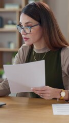 Poster - Documents, laptop and reading with mature woman at desk in office for administration or research update. Computer, review and planning with professional employee in workplace for design feedback