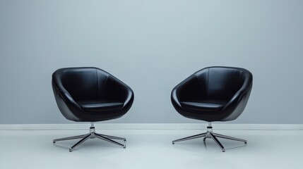 Two modern black chairs facing each other against a minimalist gray wall.