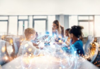 A blurred image of people in an educational setting with a glowing globe in the foreground. The bokeh effect creates a sense of movement and energy.