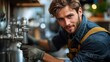 © Wiseman - young skilled plumber in uniform repairing pipes with professional tools in modern kitchen setting.image