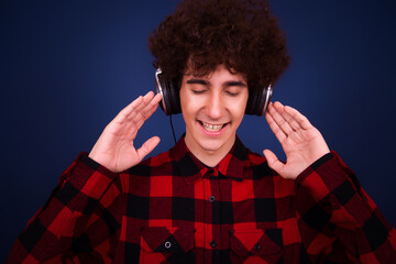 Funny skinny curly guy listening to music on headphones. Retro style.