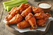 © Goolya - Delicious buffalo wings served with celery and dipping sauce on wood