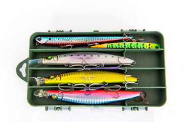 A collection of beautiful and colourful fishing lures for topwater fishing in a storage box isolated in white.