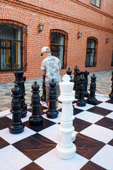 a young man is playing a game of chess with a large white king