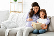 © Prostock-studio - Family time. Preschool girl and her expecting mom reading exciting book at home, copy space